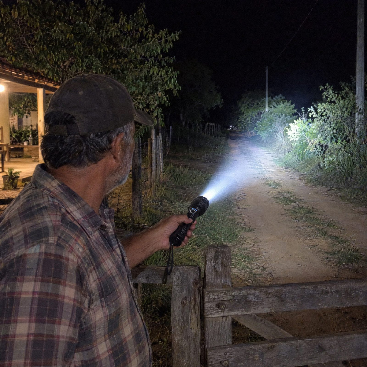 Homem usando a Lanterna Tática Carbon numa estrada de terra à noite